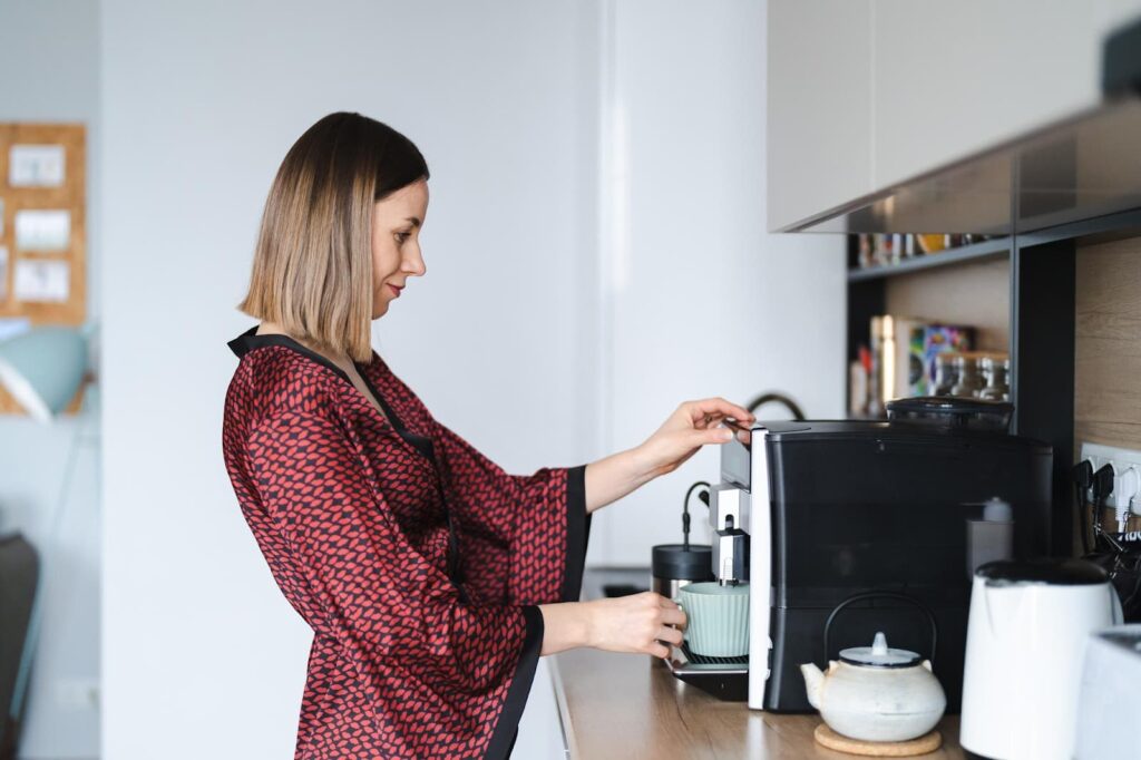 Woman using a coffee machine to make coffee at home