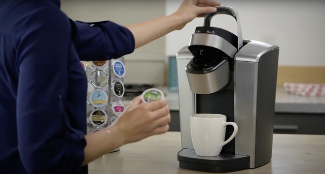 Woman putting capsule into coffee machine